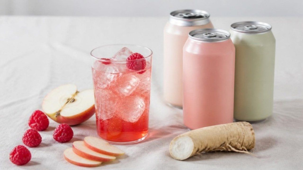 Pastel soda cans with a glass of fruit soda, apple slices and raspberries